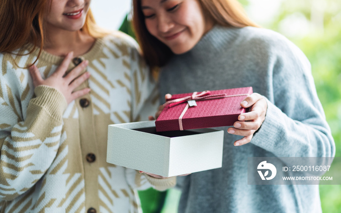 Surprised young women opening a gift box together