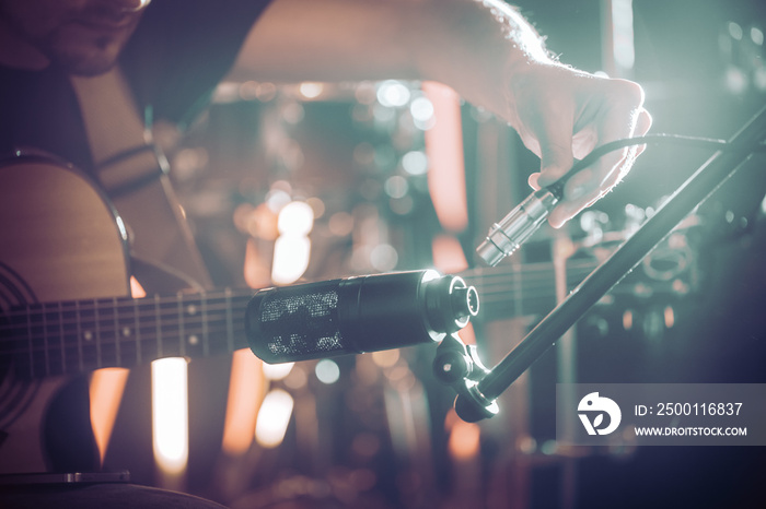 The musician connects the microphone to record an acoustic guitar close-up, in a recording Studio or concert hall.