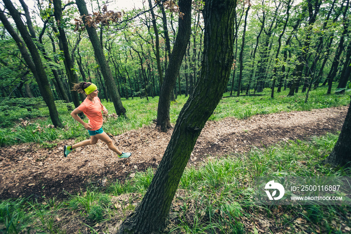 Young woman running in green forest. Endurance sport.