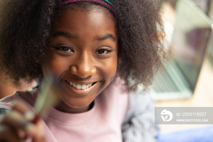 partial african american girl smiley teeth holding paint brush with blur laptop background copy spac