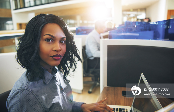 Young businesswoman working on a laptop in her office cubicle