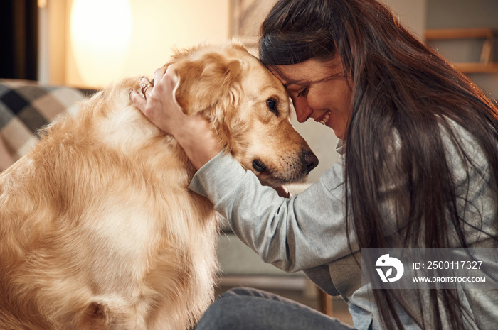 Close up view, portrait. Woman is with golden retriever dog at home