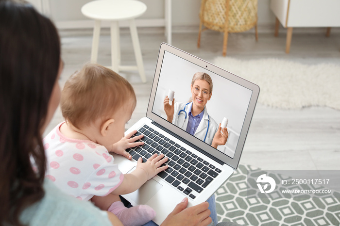 Young woman with her baby getting online consultation at home