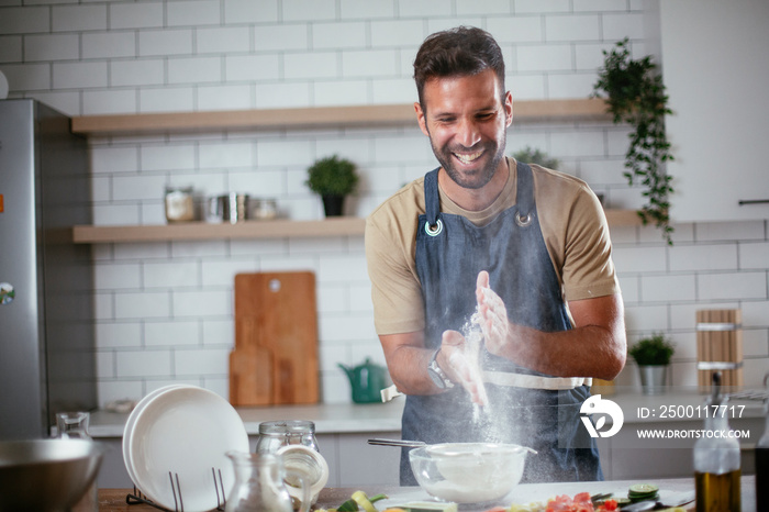 Happy man baking in the kitchen. Man making delicious food at home..