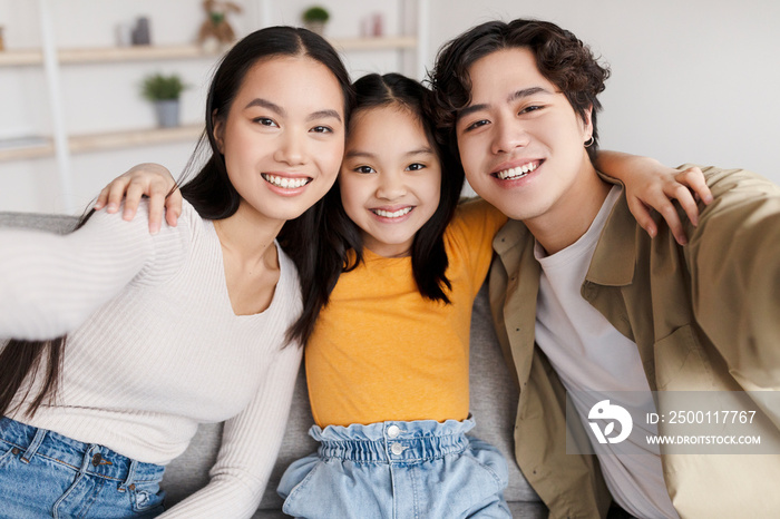 Smiling teenager korean girl, millennial woman and man make family selfie on gadget in minimalist living room