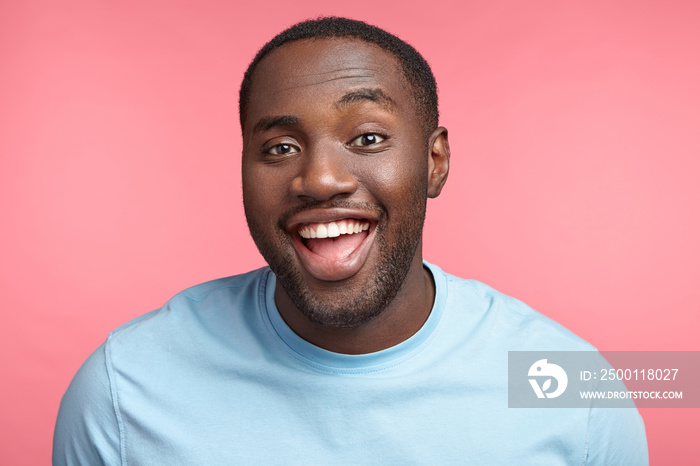 Happy dark skinned fat man laughs at good joke, has white perfect teeth, dressed casually, looks with excited expression, rejoices success, being lucky freelancer. People and positiveness concept