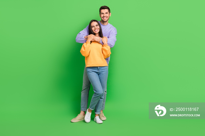 Full length portrait of two peaceful positive people cuddle have good mood isolated on green color background