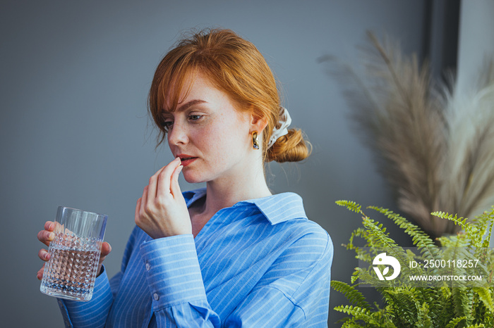 Close up woman taking white round pill, holding water glass in hand, happy young female taking supplement, daily vitamins for hair and skin, natural beauty, healthy lifestyle