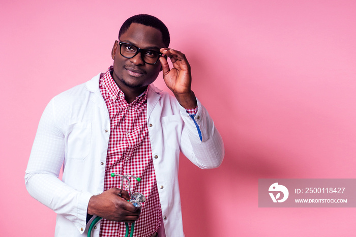 happy male african medical surgeon cardiologist doctor in a white coat on a pink background in the studio.