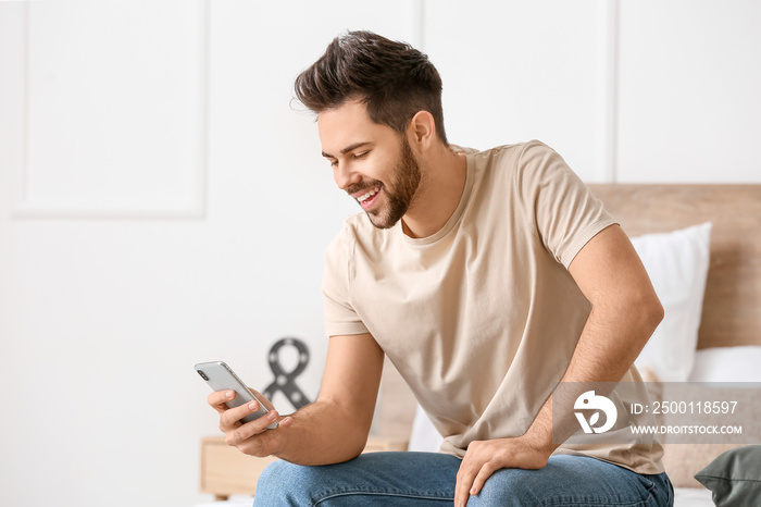 Happy young man with mobile phone at home