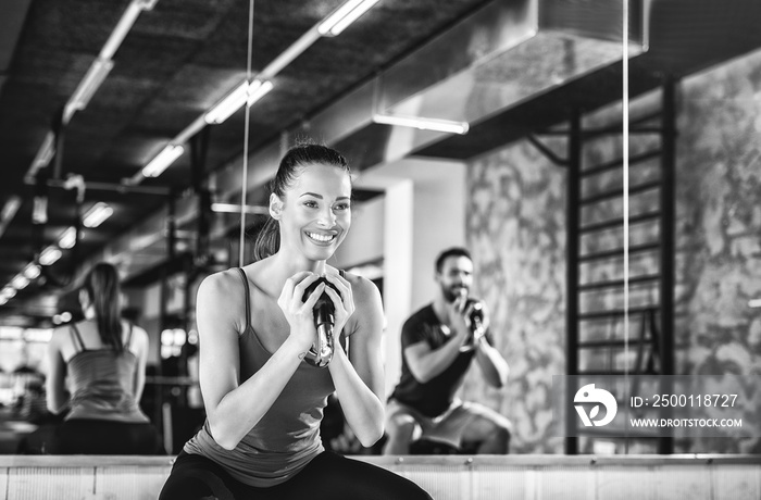 Black and white photo of beautiful female exercising with dumbbells at the gym.