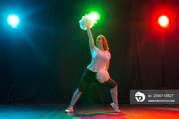 Cheerleading young woman dancing with pom-poms on colourful background