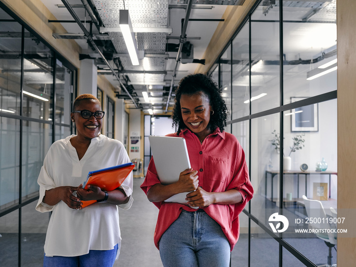 Two women walking in office hallway