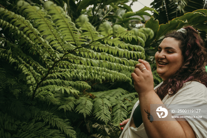 portrait of a plus size jewish woman smiling and looking at ferns