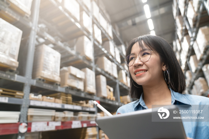 Close up of young attractive asian woman, auditor or trainee staff work stocktaking inventory in warehouse store by computer tablet with wide angle view. Asian entrepreneur or small business concept.