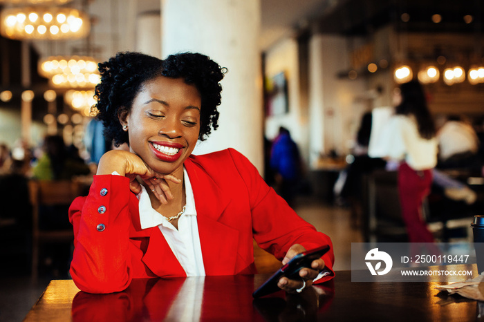 Portrait of a smiling business woman sitting in a cafe holding phone