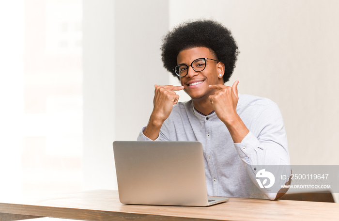 Young black man using his laptop smiles, pointing mouth