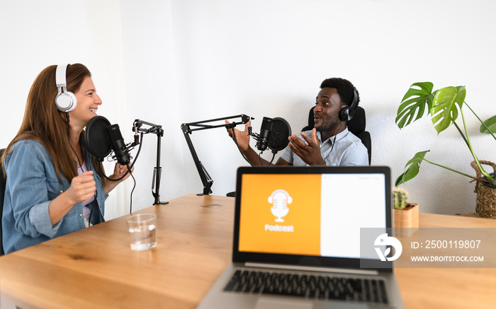 Multiracial people recording a podcast using microphone and laptop from home studio