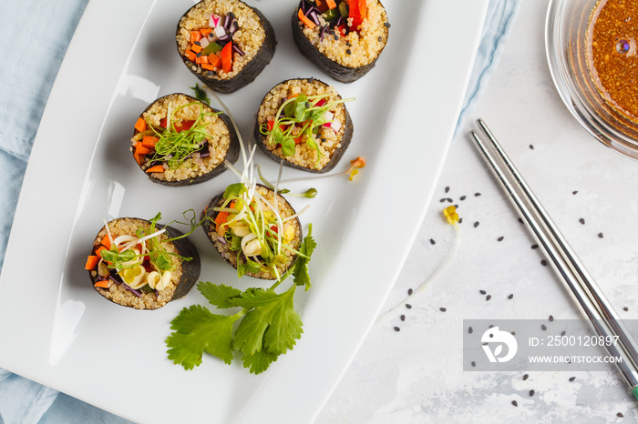 Vegan sushi rolls with quinoa, vegetables and soy-nut sauce on a white plate, light background. Top view. Vegan Healthy Food Concept.