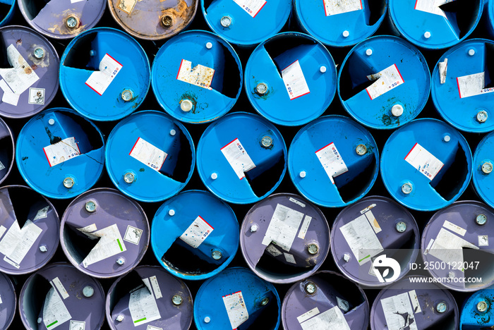 Old chemical barrels. Blue and purple oil drum. Steel oil tank. Toxic waste warehouse. Hazard chemical barrel with warning label. Industrial waste in metal drum. Hazard waste storage in factory.