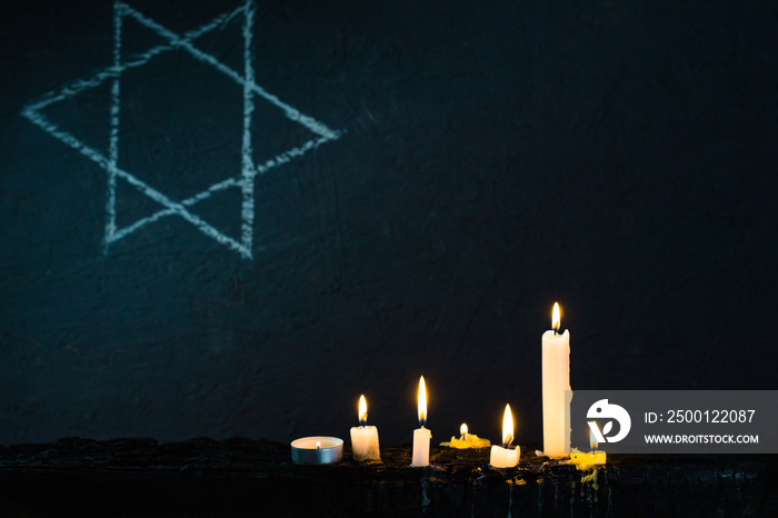 Five burning candles and the Star of David against a black background.