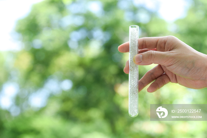 Hand holding Pet polyester chips,Plastic pet polyester chips,Chips bright in test tube with green blurred background.Chemical concept