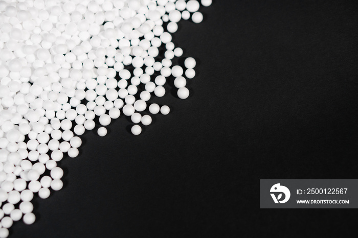 White Polystyrene foam beads on black background with copy space, waste cushioning material in luxury packaging