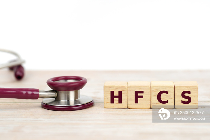 Acronym for HFCS (High Fructose Corn Syrup), word on Wooden cube with stethoscope,  The dangers of eating sugar. Medical concept.