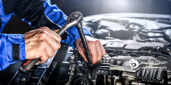 Auto mechanic working on car broken engine in mechanics service or garage.