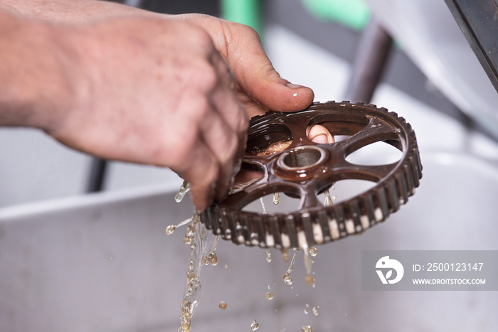 Car mechanic is cleaning and mantaining gear .