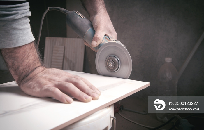 Worker cutting a tile with a grinder.