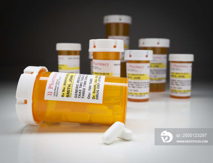 Medicine Bottles and Pills on Reflective Surface With Grey Backg