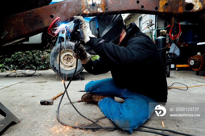 Vintage restorer, man welding old jeep truck