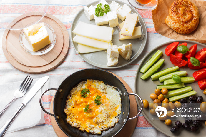 Traditional Turkish breakfast - fried eggs, fresh vegetables, olives, cheese, cake and tea