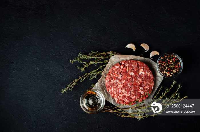 Fresh raw minced meat for meatballs with spices on a black background. Cooked raw cutlet on parchment paper.