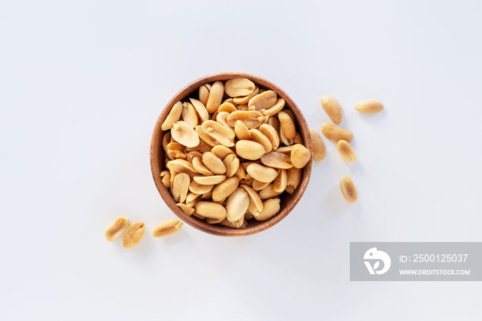 Roasted salted peanuts in wooden bowl on white background.