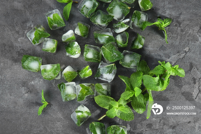 Mint near ice cubes with frozen leaves inside, on grey background