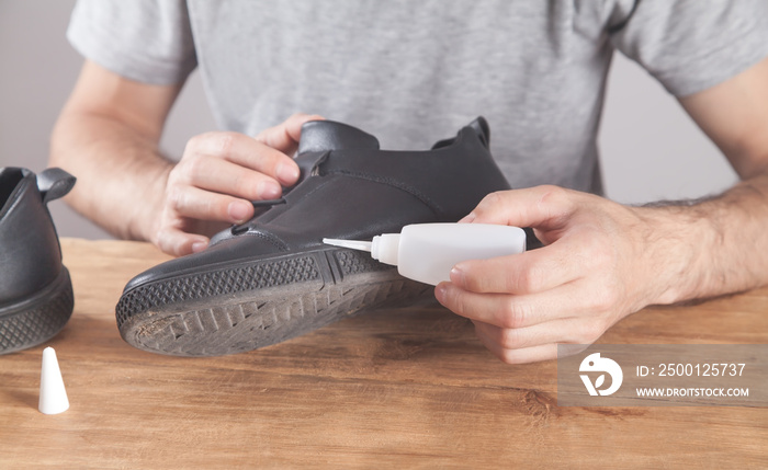 Man fixing shoe with a glue.