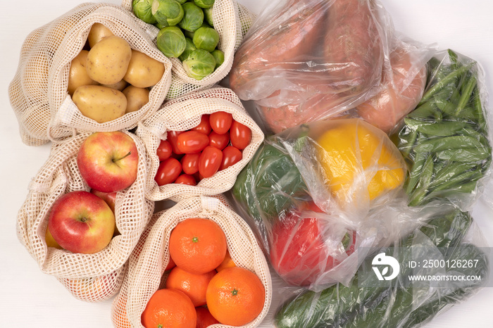 Zero waste vs plastic packaging. Fruits and vegetables in eco friendly reusable cotton bags and in plastic bags, top view with copy space