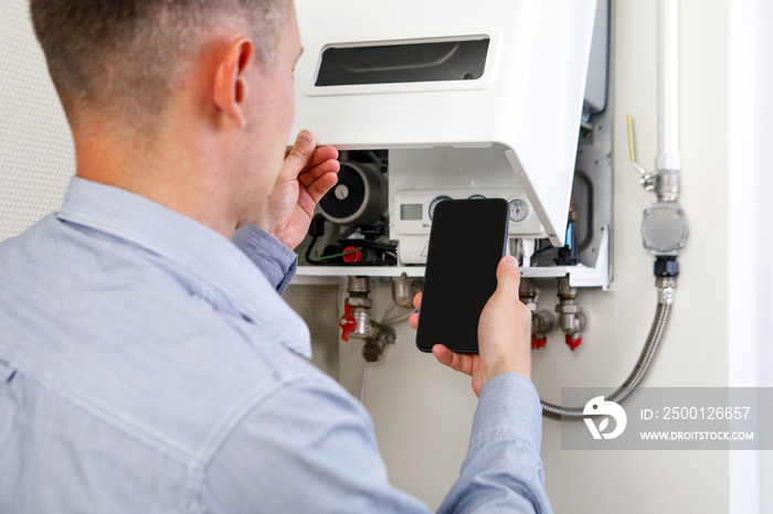 online diagnostics of household appliances via a mobile phone. a man repairing a boiler