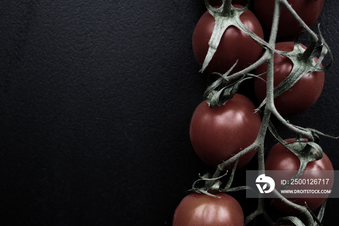 red cherry tomatoes on black board with free space for text