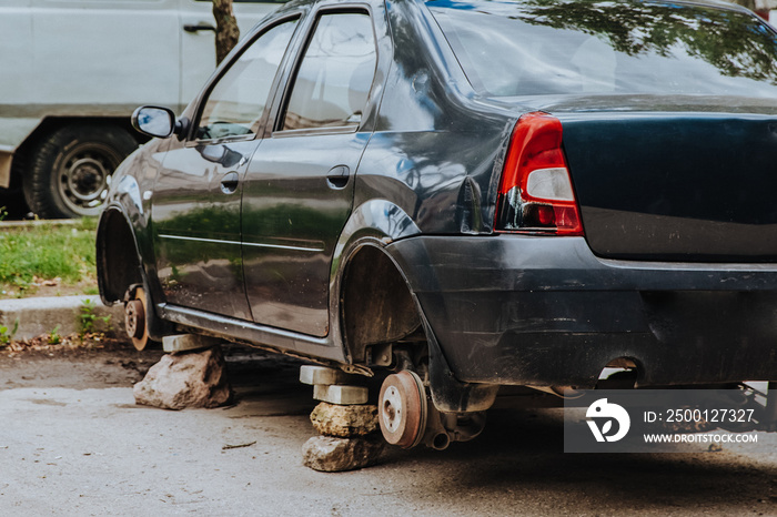 A broken passenger car without wheels stands on bricks