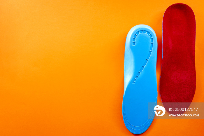 Foot support and healthy feet concept with orthopedic shoe insoles isolated on orange background with copy space