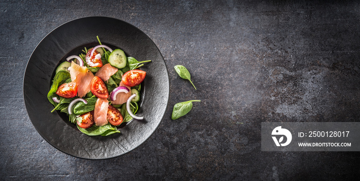 Salmon salad with vegetable in plate on dark kitchen table - Top of view