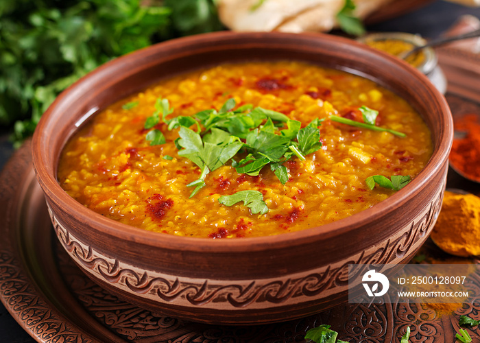 Indian dal. Traditional Indian soup lentils.  Indian Dhal spicy curry in bowl, spices, herbs, rustic black wooden background. Authentic Indian dish. Overhead