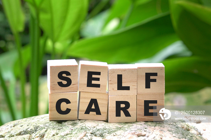 Self care word on wood cubes on green nature background. Take care of yourself message.