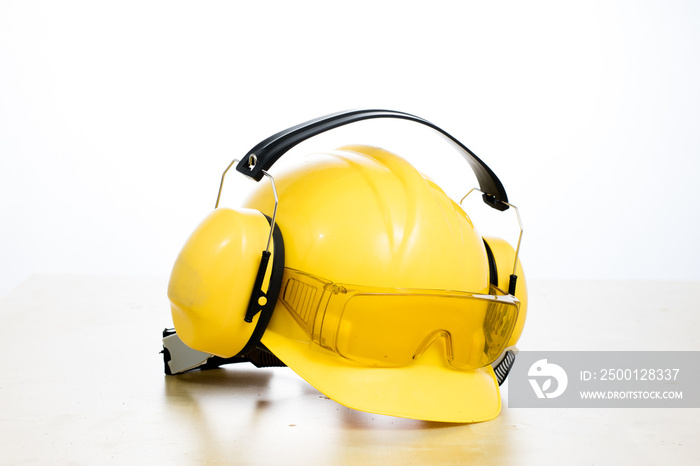 Protective helmet and work boots on a wooden table. Safety and health protection accessories for construction workers.