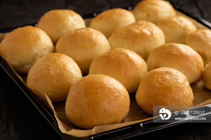 Homemade potato bread rolls on wooden tray.