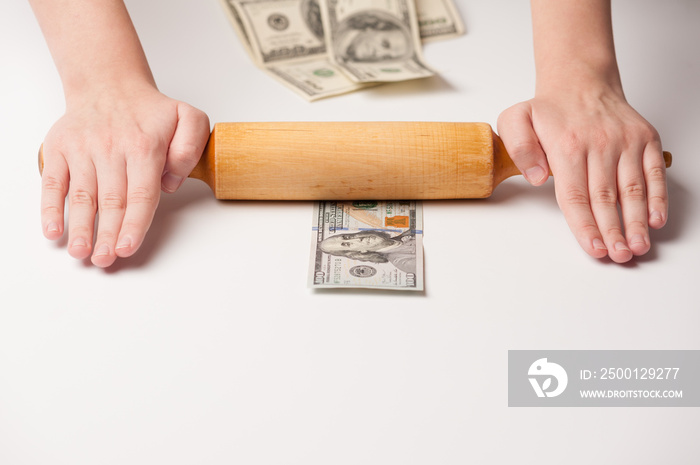 Images on the topic of world economics and finance. Allegory of financial cuisine. The rolling pin and chef’s hands roll out the bill of one hundred euro.