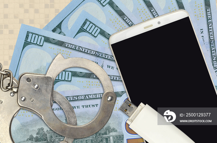 100 US dollars bills and smartphone with police handcuffs. Concept of hackers phishing attacks, illegal scam or malware soft distribution